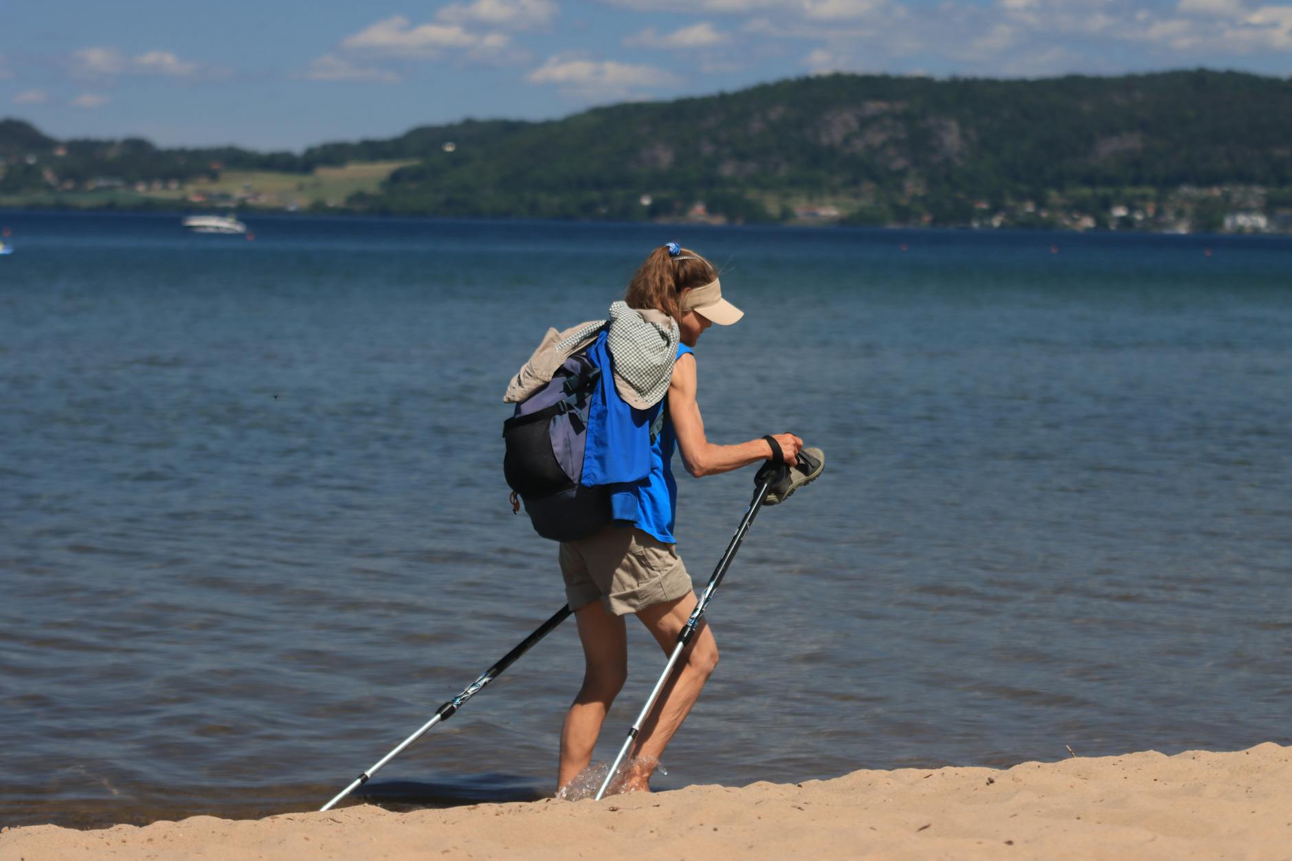 Z kijkami przez wydmy: nordic walking nad morzem w okolicach Wicia Kobieta z kijkami nordic walking idąca brzegiem morza po piasku